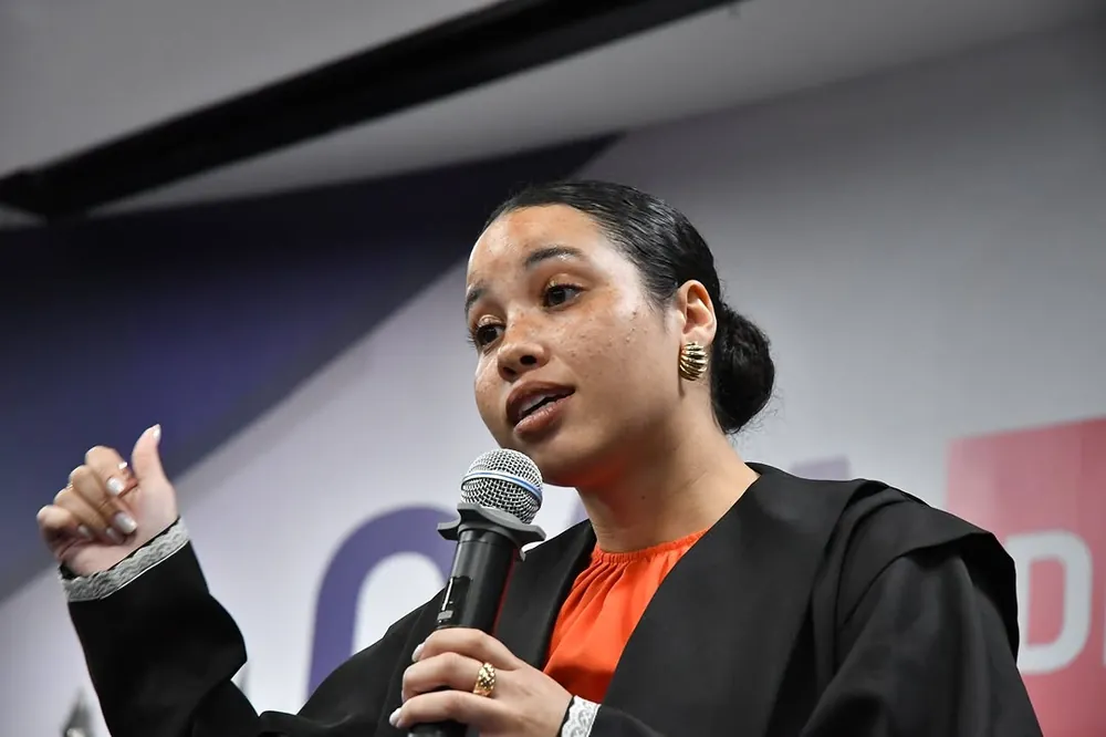 Isabella Diniz de beca, falando ao microfone no auditório da OAB/DF