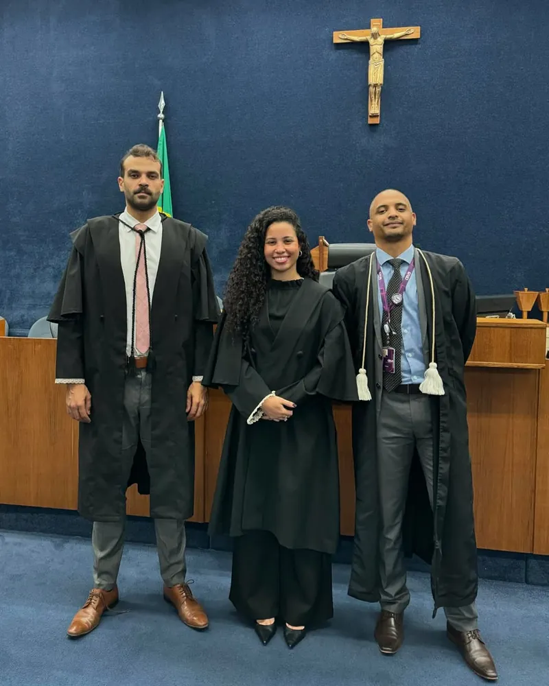 Isabella Diniz de beca, entre dois advogados, no plenário do júri de Brasília